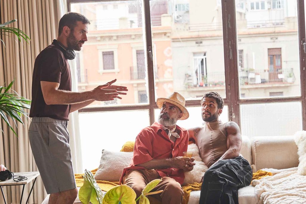 Queer cinema behind the scenes image of director guiding performers in a sunlit apartment setting