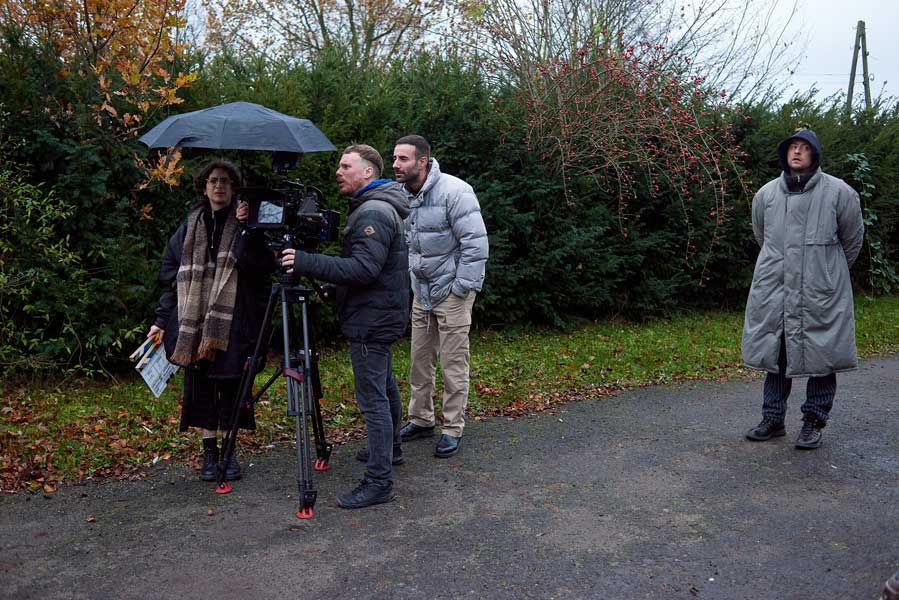 Queer cinema behind the scenes image of crew preparing an outdoor film shoot on an overcast day