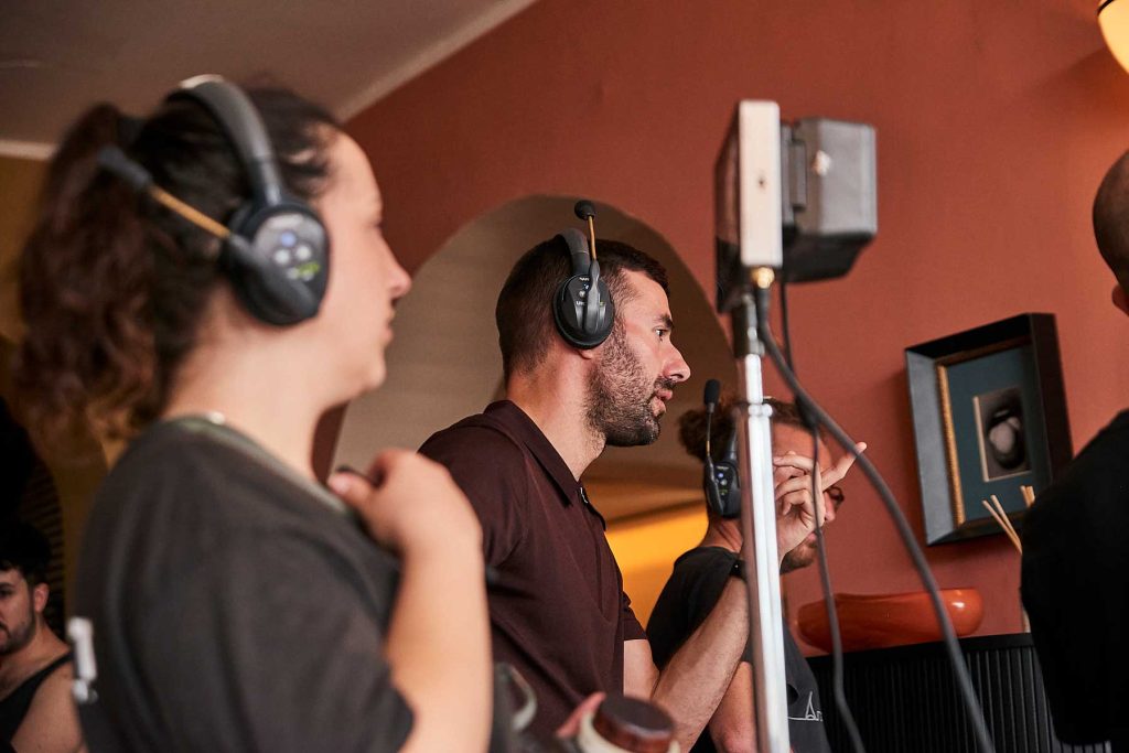 Queer cinema behind the scenes image of director and crew coordinating a film scene on set