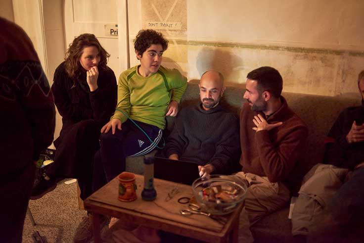 Queer cinema behind the scenes image of director and crew reviewing footage together in a casual interior setting