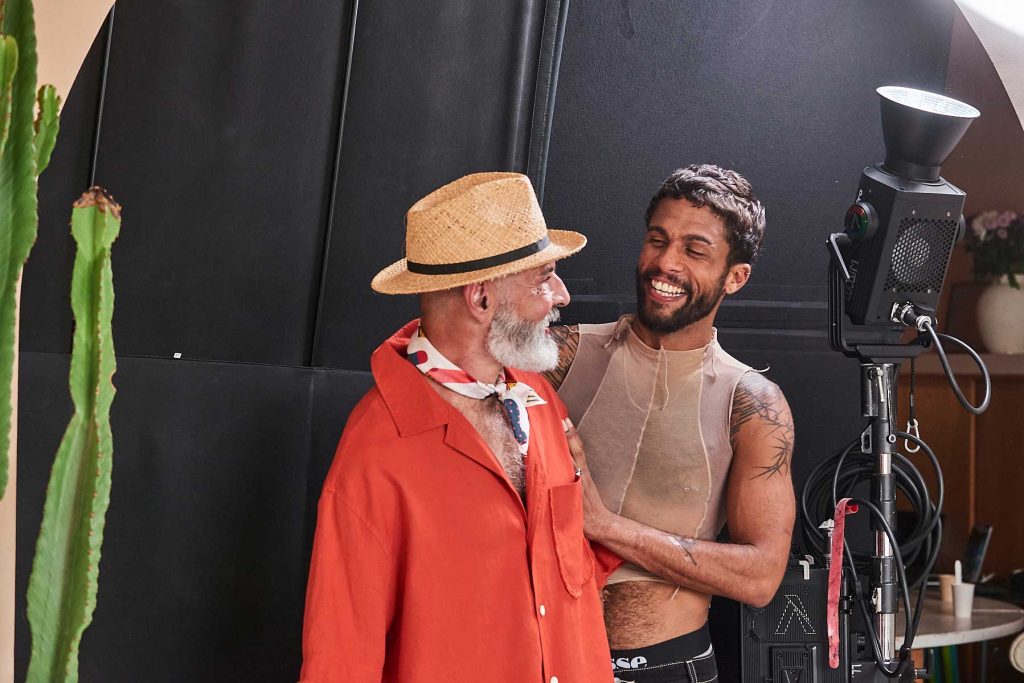 Queer cinema behind the scenes image of two performers laughing together beside studio lighting equipment